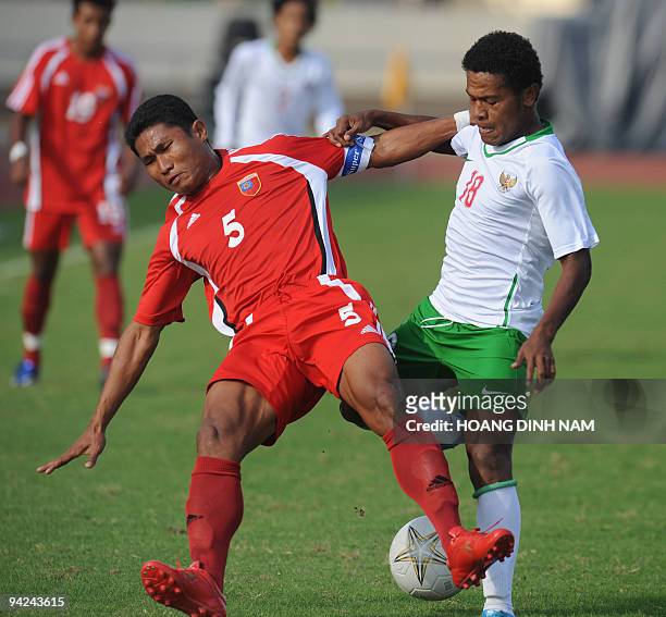 Stevie Bonsapia of Indonesia fights for the ball with Khin Maung Lwin of Myanmar during their preliminary football match at the 25th Southeast Asian...