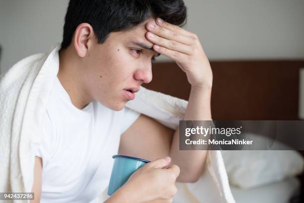 young hispanic man catching a cold - cold virus stock pictures, royalty-free photos & images