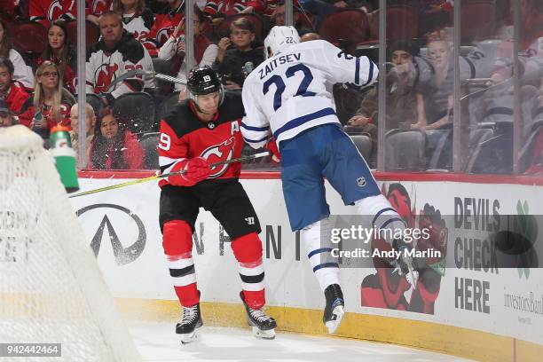 Travis Zajac of the New Jersey Devils and Nikita Zaitsev of the Toronto Maple Leafs battle for the puck during the game at Prudential Center on April...