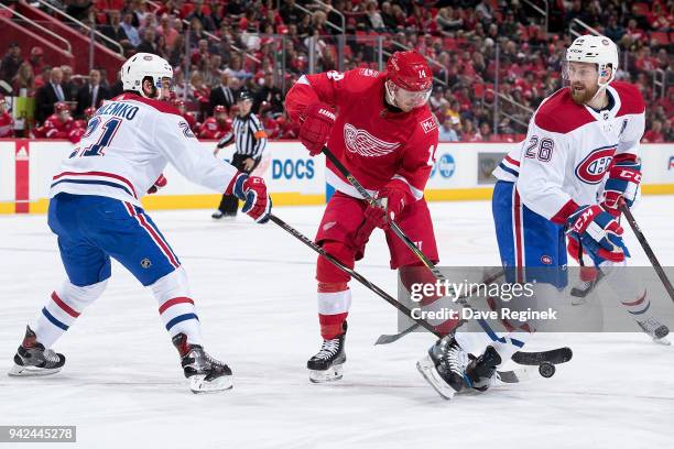 Gustav Nyquist of the Detroit Red Wings battles for the puck with David Schlemko and Jeff Petry of the Montreal Canadiens during an NHL game at...