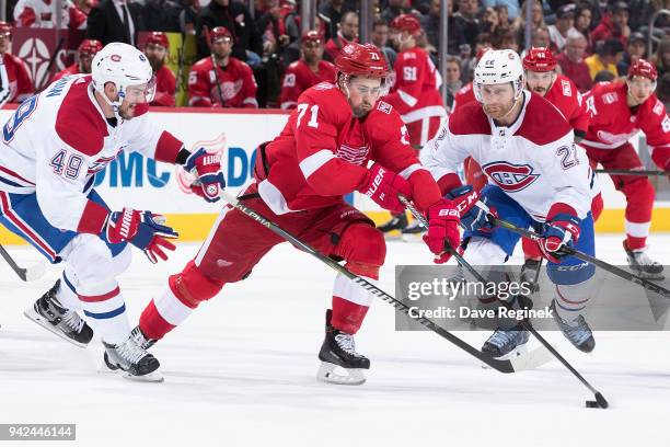 Dylan Larkin of the Detroit Red Wings battles for the puck with Logan Shaw and Karl Alzner of the Montreal Canadiens during an NHL game at Little...