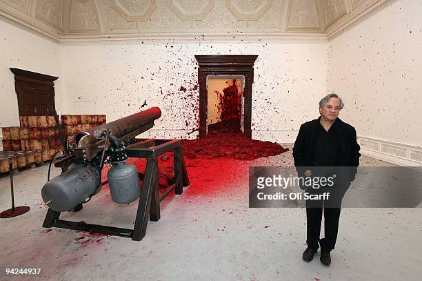Sculptor Anish Kapoor poses for photographs in front of his artwork 'Shooting into the Corner' in the Royal Academy of Arts on December 10, 2009 in...