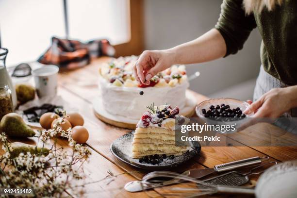 女性が誕生日の祝賀会のためのケーキをカット - 焼き菓子 ストックフォトと画像