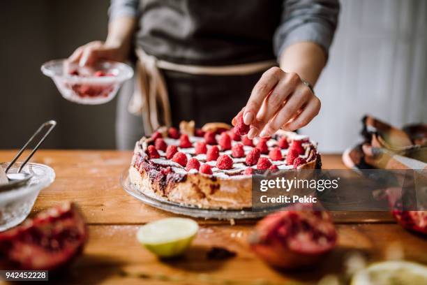 adding raspberries to tasteful blackberry pie - cake pie stock pictures, royalty-free photos & images