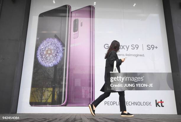 Woman walks past an advertisement for the Samsung Galaxy S9 at a mobile phone shop in Seoul on April 6, 2018. - Samsung Electronics on April 6...