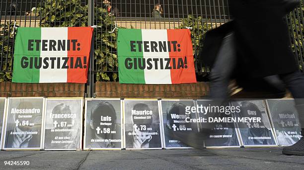 Person walks past by banners attached on Turin's courthouse's fence on the first day of trial of two-former Eternit executives, on December 10, 2009....