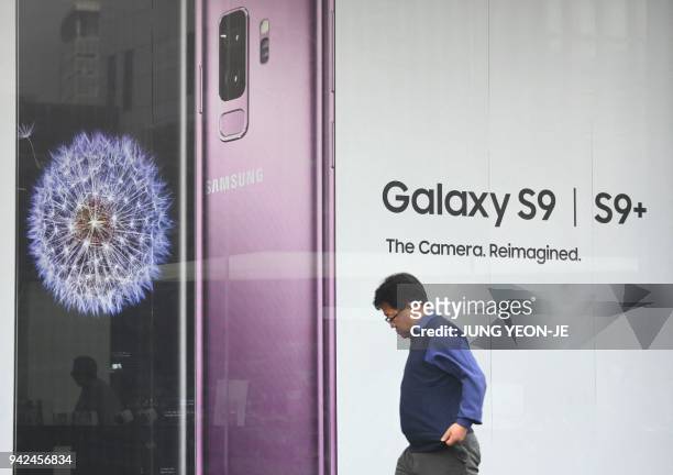 Man walks past an advertisement for the Samsung Galaxy S9 at a mobile phone shop in Seoul on April 6, 2018. - Samsung Electronics on April 6 flagged...