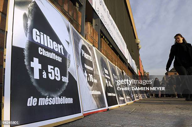 Woman walks past banners posted by the Swiss victim association on Turin's courthouse fence on the first day of trial of two-former Eternit...