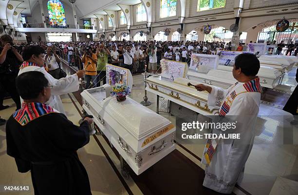 Catholic priests bless the coffins of slain journalists after the funeral mass in General Santos City, south Cotabato province on December 4, 2009....