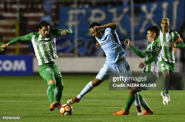Leonel Justiniano of Bolivia's Bolivar vies for the ball with Jorman Campuzano and Gonzalo Castellani of Atletico Nacional of Colombia during their...