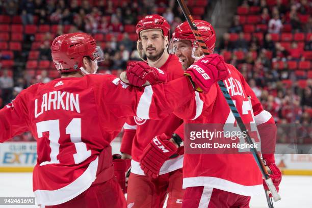 Darren Helm of the Detroit Red Wings celebrates his third period goal with teammates Jonathan Ericsson and Dylan Larkin during an NHL game against...