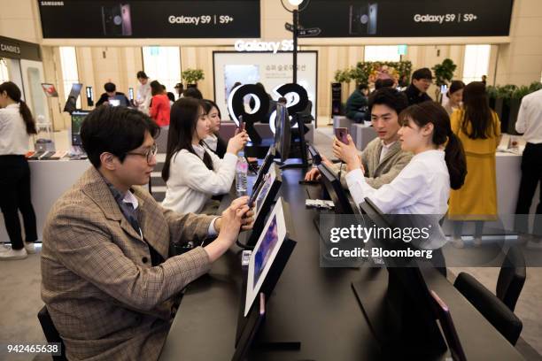 Customers try out Samsung Electronics Co. Galaxy S9 smartphones at one of the company's promotional booths in Seoul, South Korea, on Thursday, April...