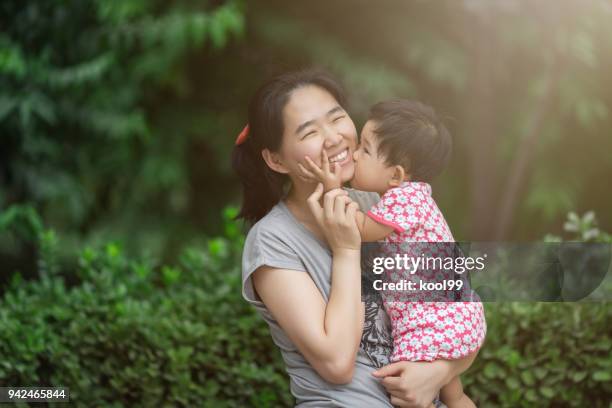 niedliche baby küssen ihre mutter - asia ray stock-fotos und bilder