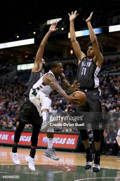 Eric Bledsoe of the Milwaukee Bucks passes the ball while being guarded by Allen Crabbe and Jarrett Allen of the Brooklyn Nets in the third quarter...