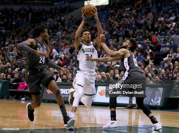 Giannis Antetokounmpo of the Milwaukee Bucks dribbles wthe ball between Rondae Hollis-Jefferson and Allen Crabbe of the Brooklyn Nets in the third...