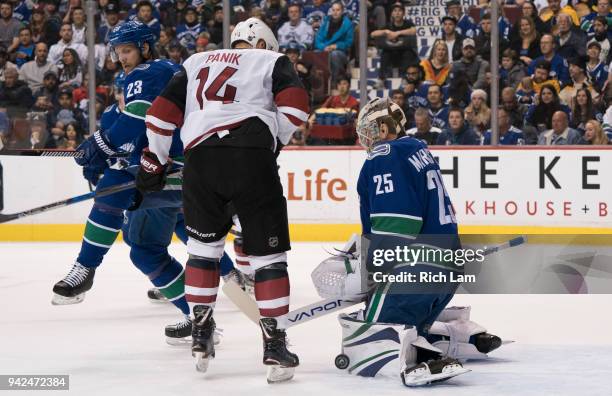 Goalie Jacob Markstrom of the Vancouver Canucks makes a save while Richard Panik of the Arizona Coyotes looks for a rebound in NHL action on April...