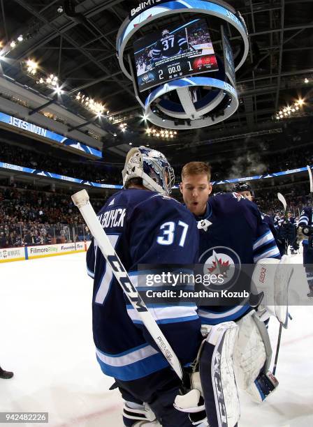 Goaltender Connor Hellebuyck of the Winnipeg Jets gets congratulated by teammate Steve Mason after a 2-1 victory over the Calgary Flames at the Bell...