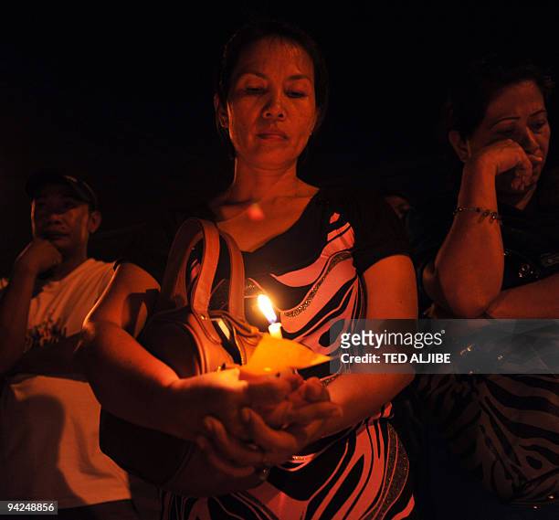Resident holds a candle during an indignation rally in the town of Koronadal, south Cotabato province on November 25 as investigators in Ampatuan...