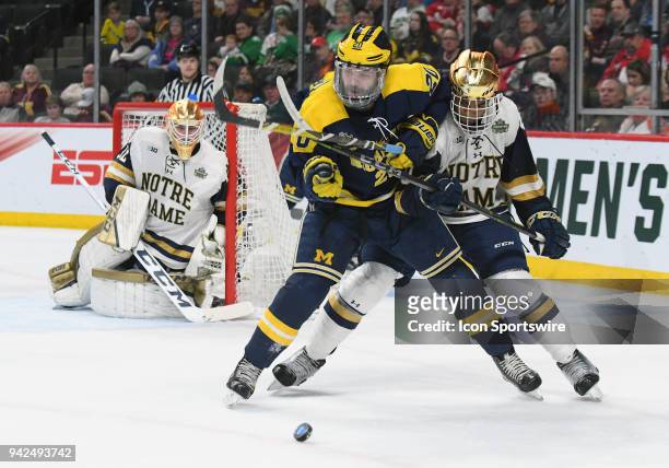 Michigan Wolverines forward Cooper Marody and Notre Dame Fighting Irish defenseman Justin Wade battle for a loose puck during a Frozen Four Semifinal...