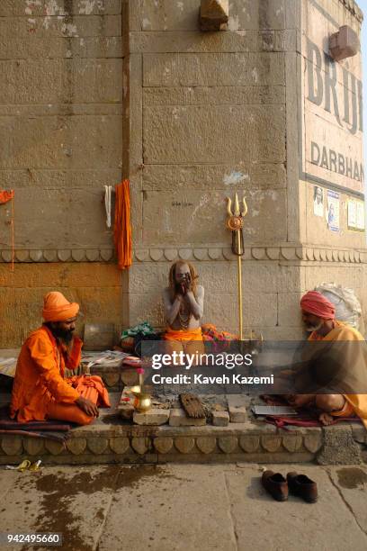 Sadhus sit smoking a chillum full of hashish on the side of Darbhanga Ghat on January 28, 2018 in Varanasi, India. Varanasi is a major religious hub...