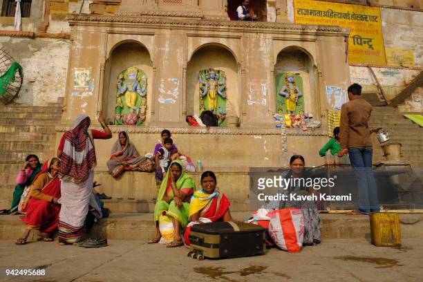 Hindu pilgrims in colorful clothes sit by the stairs of a ghat on the banks of Ganga River on January 28, 2018 in Varanasi, India. Varanasi is a...