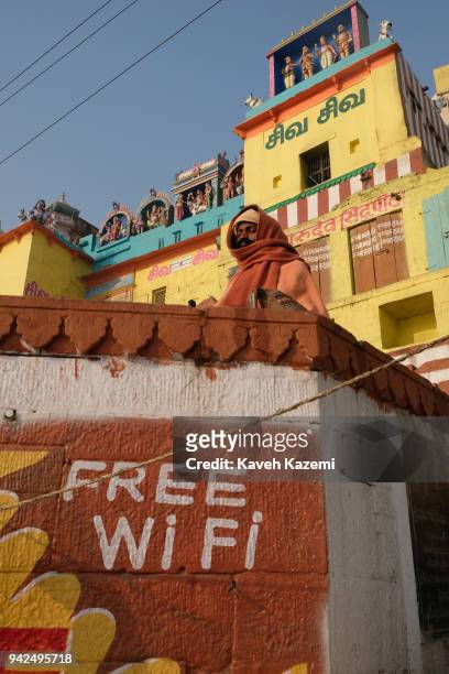 Sage man meditates while sat on a high ground above a Free Wi Fi notice in Vijayanagaram Ghat facing the Ganga River on January 28, 2018 in Varanasi,...