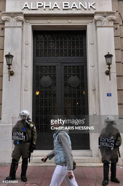 Woman passes by an Alpha bank branch as policemen stand guard in Athens on December 10, 2009. Greece said its debt had reached a record 300 billion...