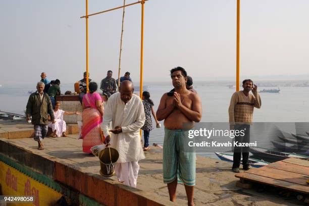 Hindu pilgrim standing on the banks of Ganga River prays towards the temples of Vijayanagaram Ghat on January 29, 2018 in Varanasi, India....