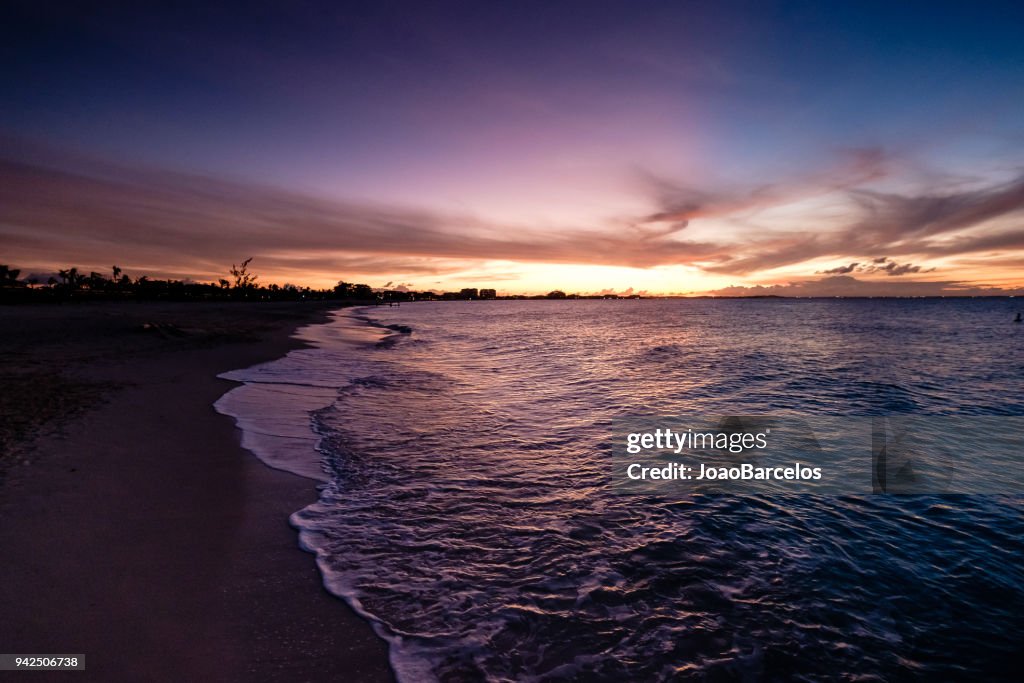 Waves crashing on beach during sunset. Beautiful orange purple skies reflecting on the ocean. Grace Bay Beach, Providenciales, Turks and Caicos.