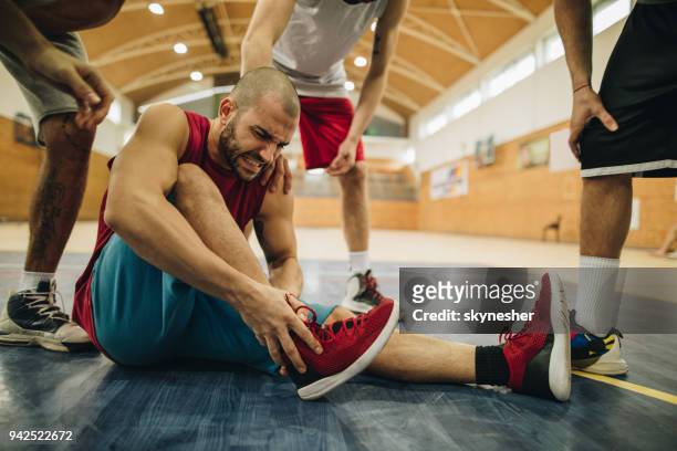 giocatore di basket infortunato che tiene la caviglia nel dolore in campo. - caviglia foto e immagini stock