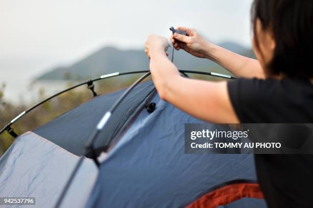 asian woman pitching tent - picchetto da tenda foto e immagini stock