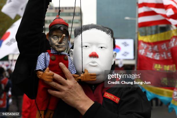 Supporter of South Korea's former president Park Geun-hye, wearing a mask of North Korean leader Kim Jong-Un holds a doll of South Korean President...