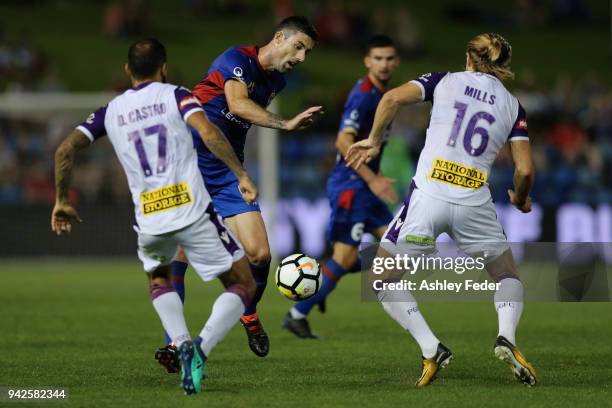 Jason Hoffman of the Jets is contested by Diego Castro and Joseph Mills of Perth Glory during the round 26 A-League match between the Newcastle jets...