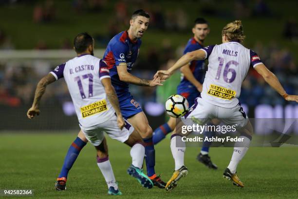 Jason Hoffman of the Jets is contested by Diego Castro and Joseph Mills of Perth Glory during the round 26 A-League match between the Newcastle jets...