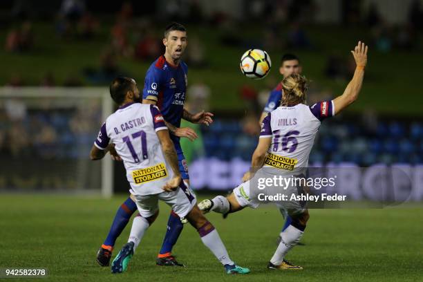 Jason Hoffman of the Jets is contested by Diego Castro and Joseph Mills of Perth Glory during the round 26 A-League match between the Newcastle jets...