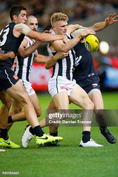 Adam Treloar of the Magpies gets a kick away as he is tackled by Jacob Weitering of the Blues during the round three AFL match between the Carlton...