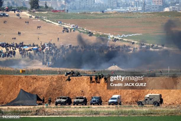 Picture taken on April 6, 2018 from the southern Israeli kibbutz of Mefallesim across the border with the Gaza strip shows Palestinian men burning...