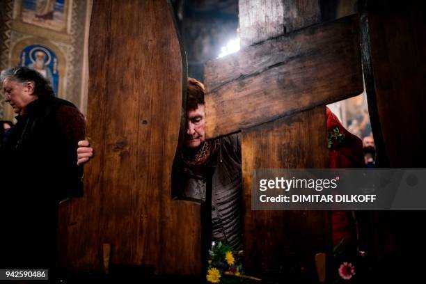 Woman prays in front of a wooden crucifix during the traditional Good Friday service at Alexander Nevsky Cathedral in Sofia on April 6, 2018. / AFP...