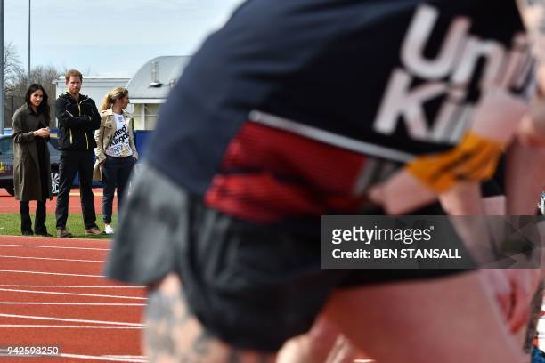 Britain's Prince Harry and his fiancee US actress Meghan Markle watch participants try out for the track and field events at the UK team trials for...