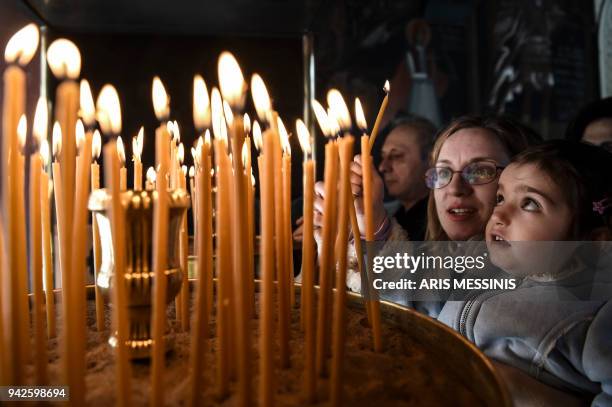 Greek Orthodox believers light candles during Good Friday's 'Apokathelosis', the lowering of Christ's dead body from the Cross, which forms a key...