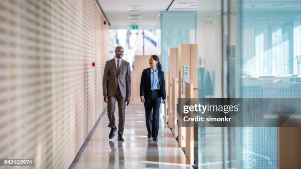 business colleagues walking in office - two people side by side stock pictures, royalty-free photos & images