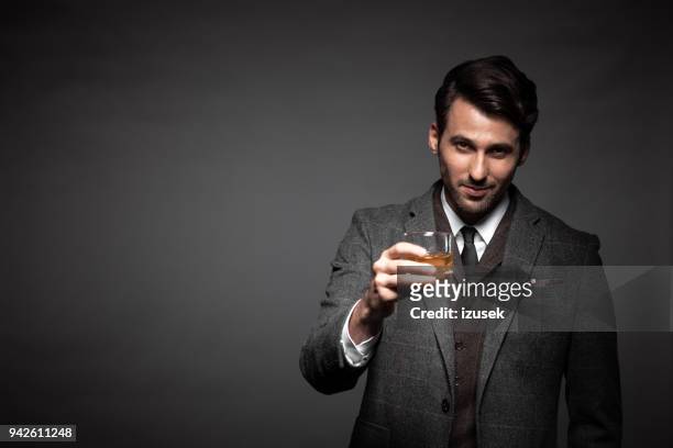 ritratto di bell'uomo che beve whisky - solo un uomo di età media foto e immagini stock