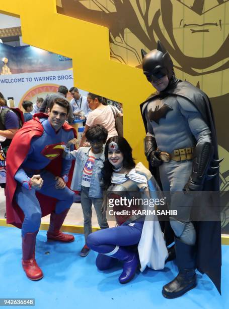 Boy poses for a picture with cosplayers dressed as Superman, Wonder Woman and Batman during the Middle East Film & Comic Con on April 6 in Dubai. /...