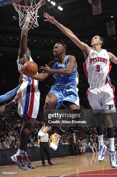 Chauncey Billups of the Denver Nuggets attempts a layup between Kwame Brown and Austin Daye of the Detroit Pistons in a game at the Palace of Auburn...