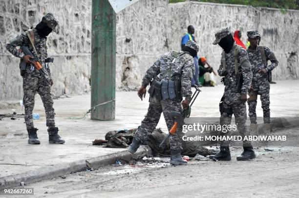 Graphic content / Somali soldiers look at the body of an alleged Al Shabab fighter who was shot dead by Somali security forces at the site of a car...