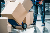Close-up view of delivery man carrying boxes on cart