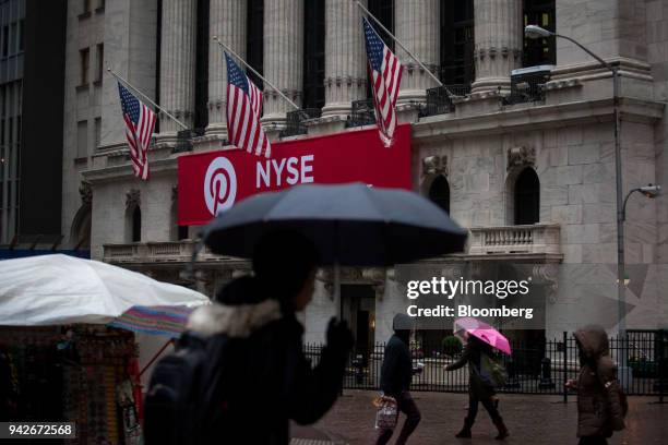 Pedestrians carrying umbrellas walk past the New York Stock Exchange in New York, U.S., on Friday, April 6, 2018. U.S. Stocks fell and Treasuries...