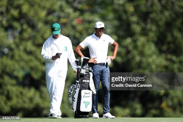 Tony Finau of the United States waits with caddie Gregory Bodine on the fifth fairway during the second round of the 2018 Masters Tournament at...