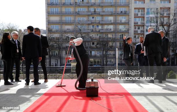 Worker vacuums the red carpet before the arrival of participants to attend the Cedre conference at The Foreign Affairs Ministry in Paris on April 6,...