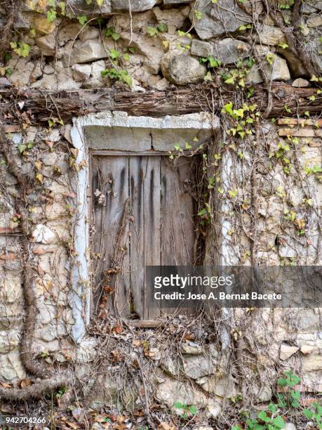full frame of a ancient  facade of a stone wall with a window of wood illuminated by the light of the sun. high resolution photography. spain. - adobe texture stockfoto's en -beelden